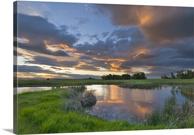 Vivid sunset clouds reflect into small pond, Mission Valley of Montana
