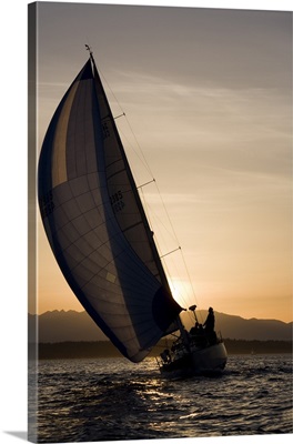 Washington, Seattle, setting sun lights yacht sailing in Elliot Bay