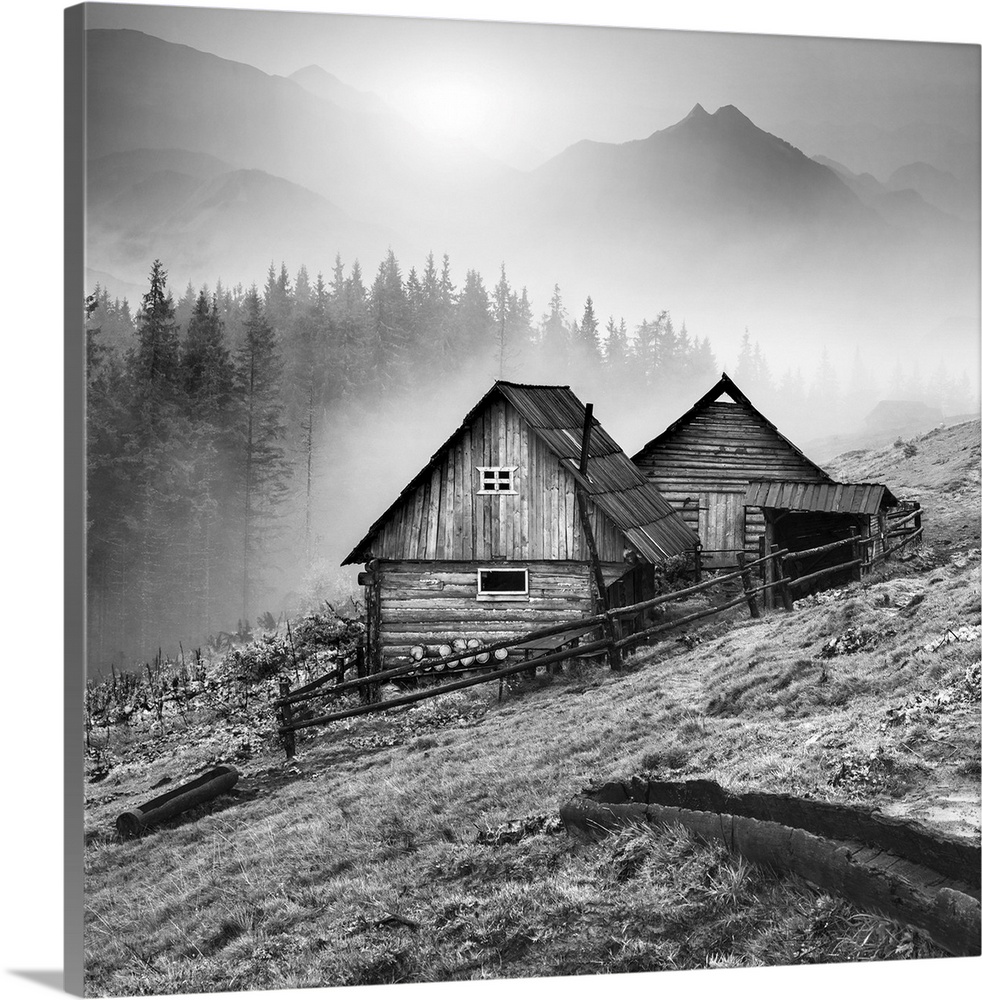Beautiful sunrise in Carpathian mountains with nature wooden houses on a forest hill. Black and white.