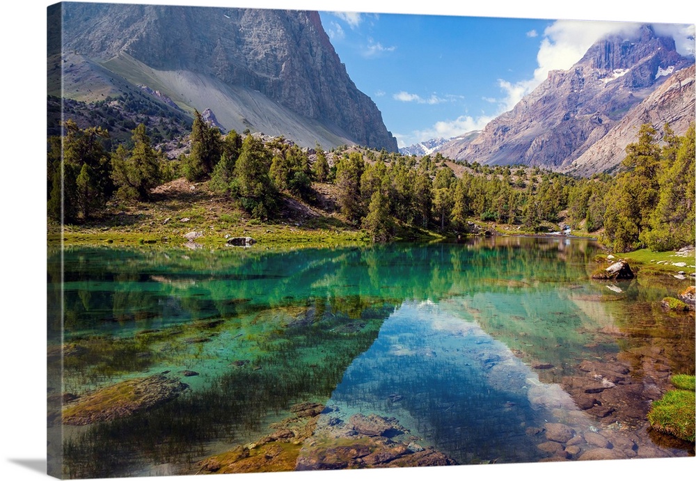 Scenic landscape with vibrant water surface forest and high mountain peak blue sky.