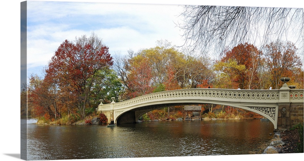 Central Park panorama in autumn with skyscrapers, foliage, lake and Bow Bridge.