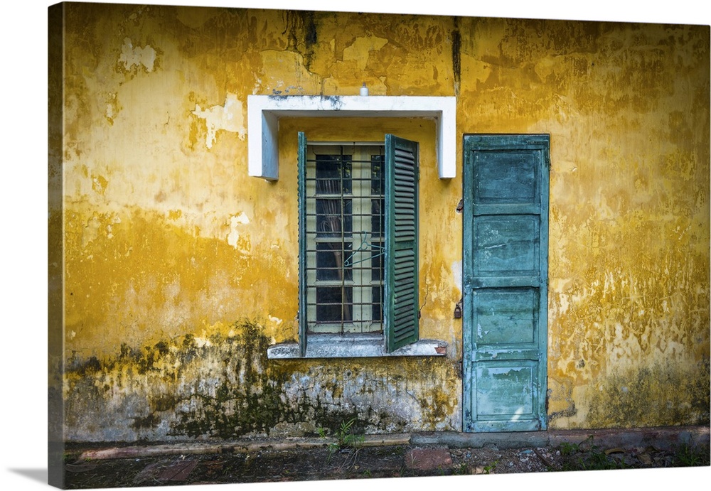 Outside view of deserted house with details in Vietnam. Old and grungy yellow wall with window and worn blue door. Abandon...