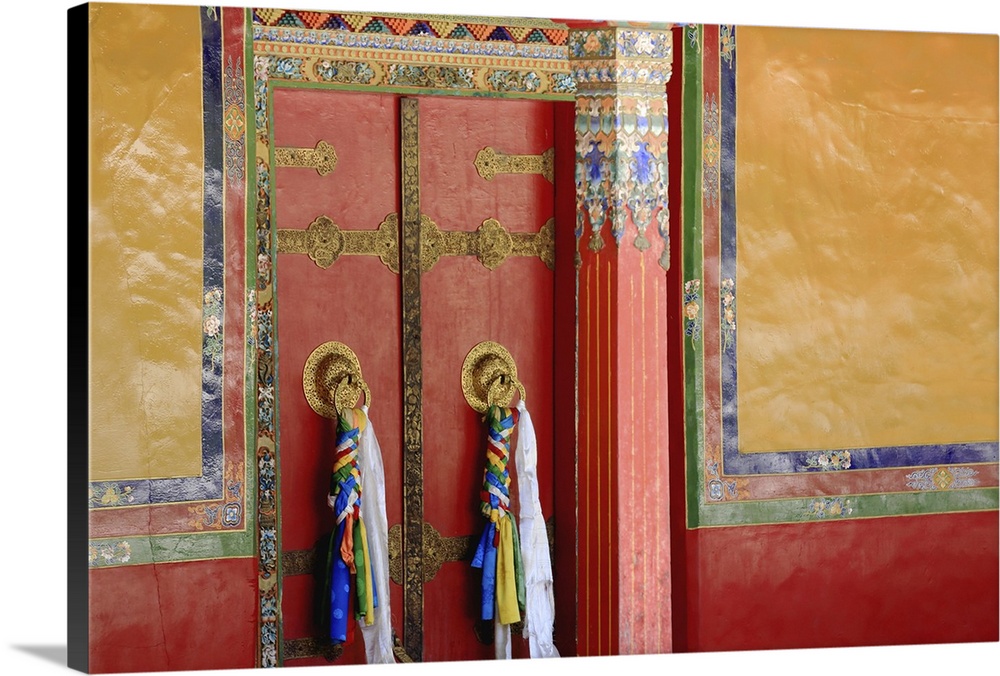 Red double door with black and gold decoration batten, a colorist doorframe, gilded doorknobs and Tibetan colored fabrics ...