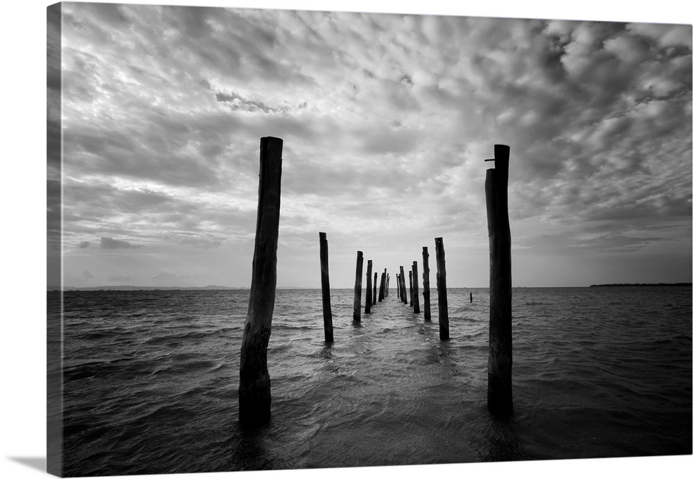 Black and white seascape with wooden pillars as leading lines.