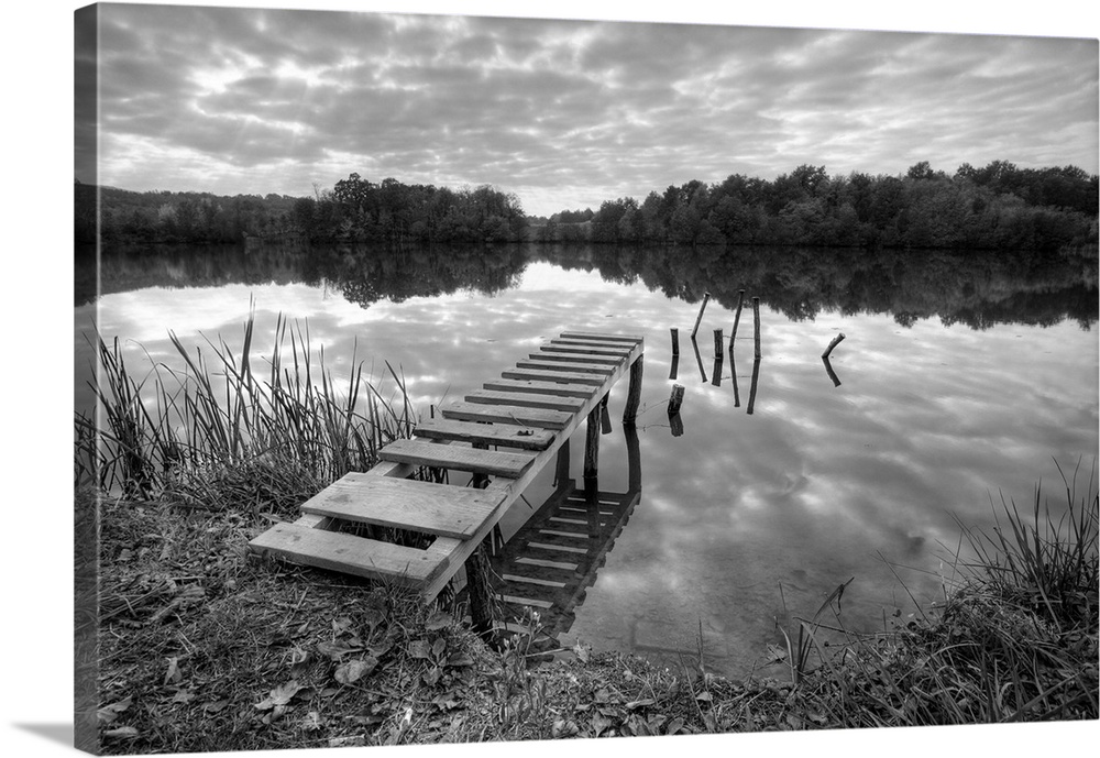 Beautiful lake with pier on cloudy day in black and white.