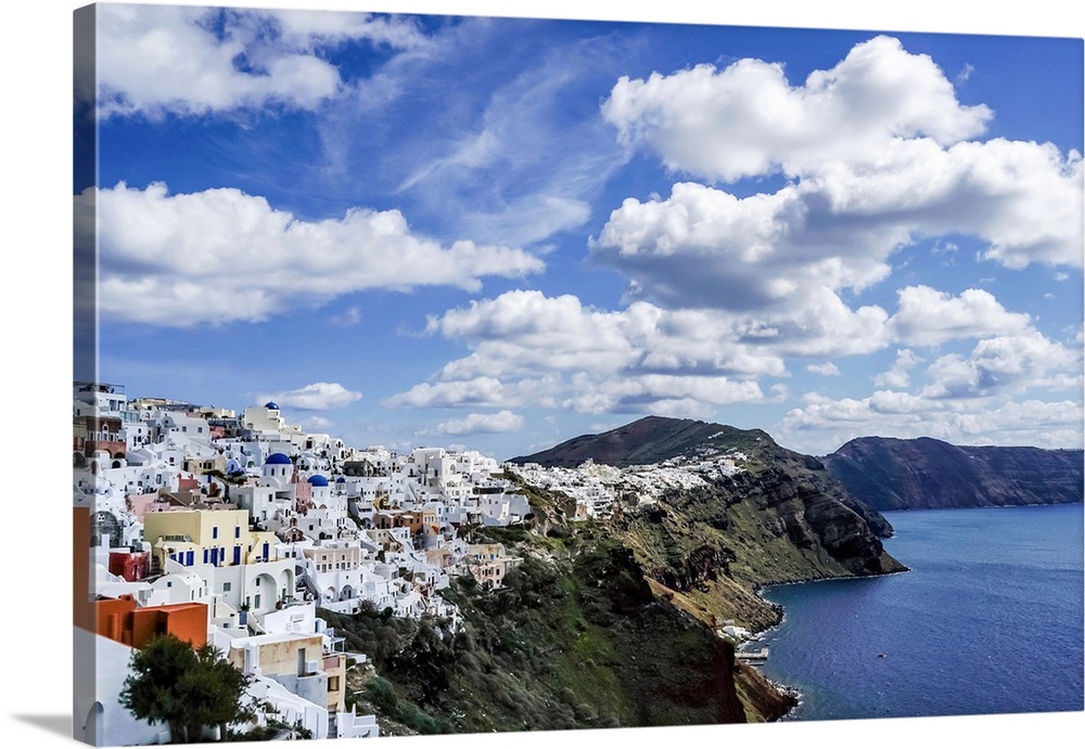White houses near tranquil sea against blue sky with clouds in Greece.