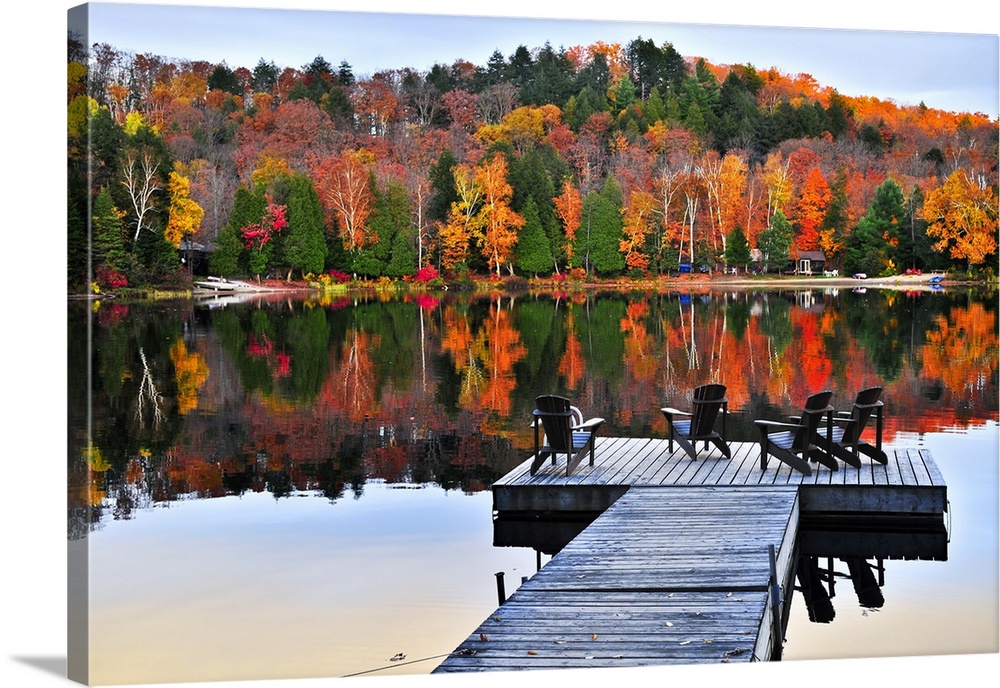 Wooden dock with chairs on calm fall lake.