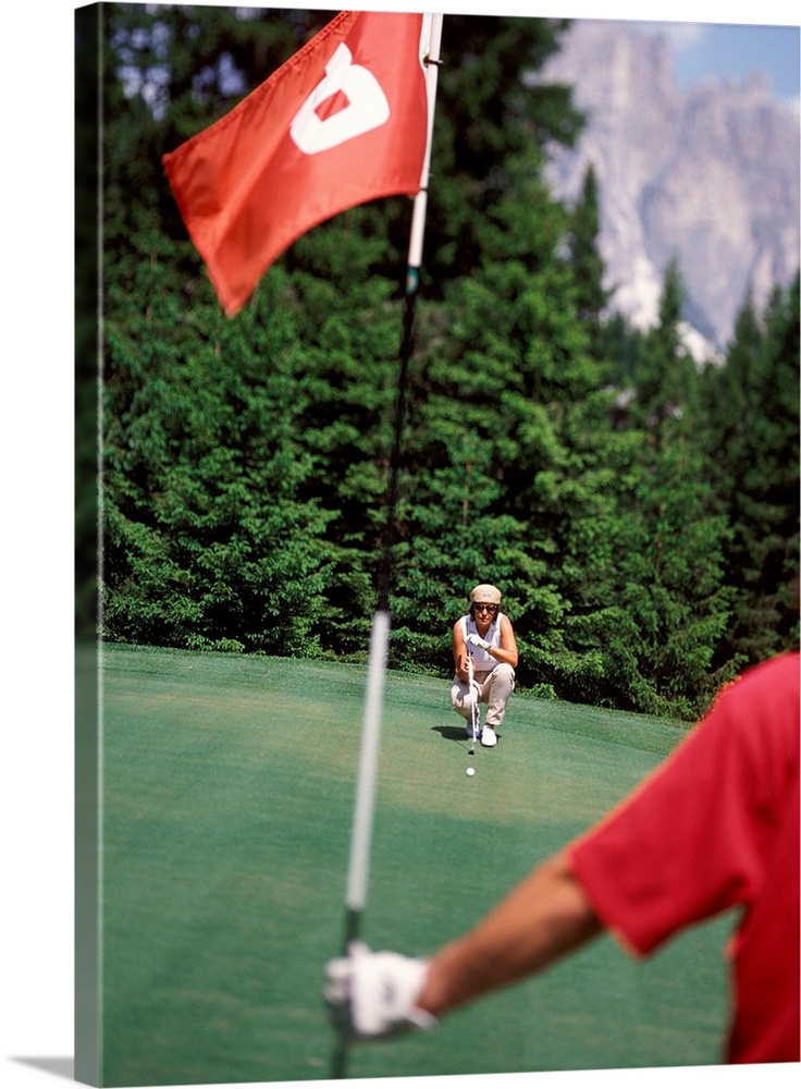 Couple playing golf, man holding flag