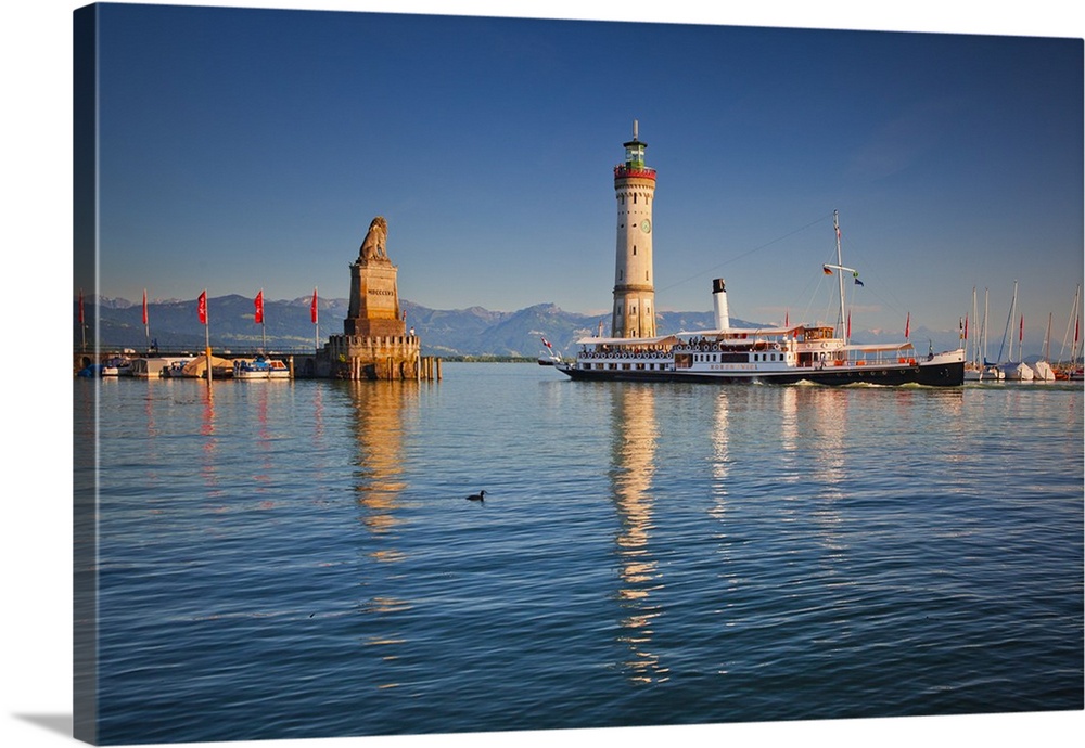 Germany, Bavaria, Lake Constance, Swabia, Schwaben, Lindau, Lighthouse and a passenger ship at the harbor entrance at sunset.