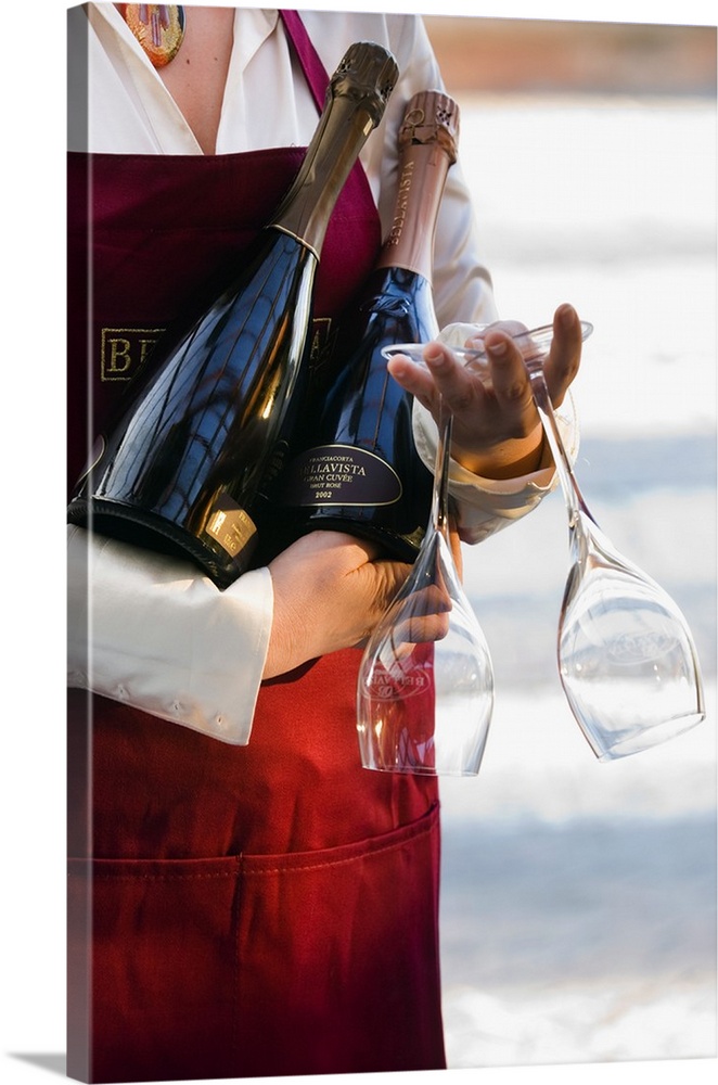 Italy, Lombardy, Waitress bringing bottles of Bellavista sparkling wine