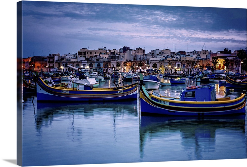 Malta, Marsaxlokk, Mediterranean sea, Luzzu, traditional fishing boats and Marsaxlokk harbor at dusk.