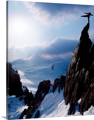Rock climber at the peak of a snow capped mountain