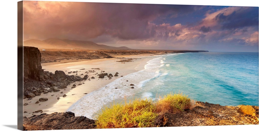 Spain, Canary Islands, Fuerteventura, Beach and rugged coastline at dawn.