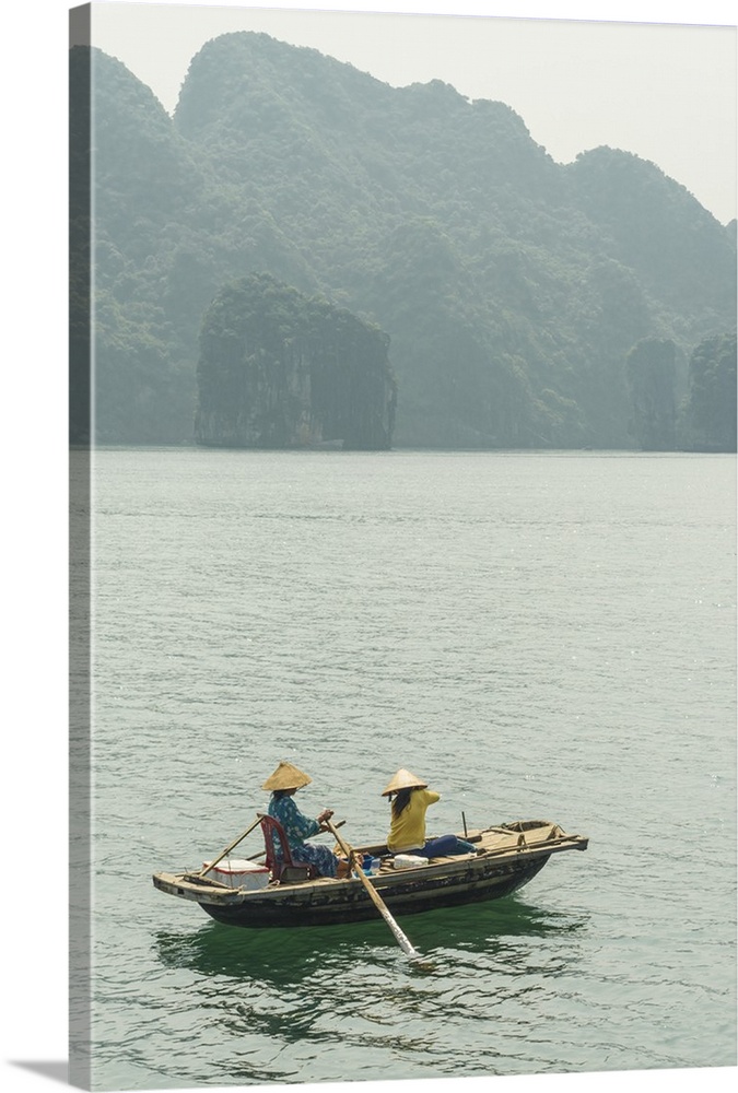 Vietnam, Northeast, North Vietnam, Coast, Halong Bay, Women in a rowing boat with Cat Ba Island in the background.