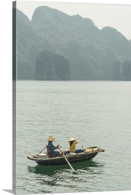 Vietnam, Halong Bay, Women in a rowing boat with Cat Ba Island in the background