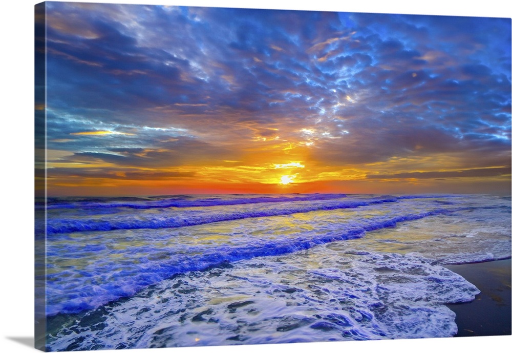 Breaking lavender waves turn into white sea foam as they meet the shore. A beautiful lavender and blue sunset along the be...