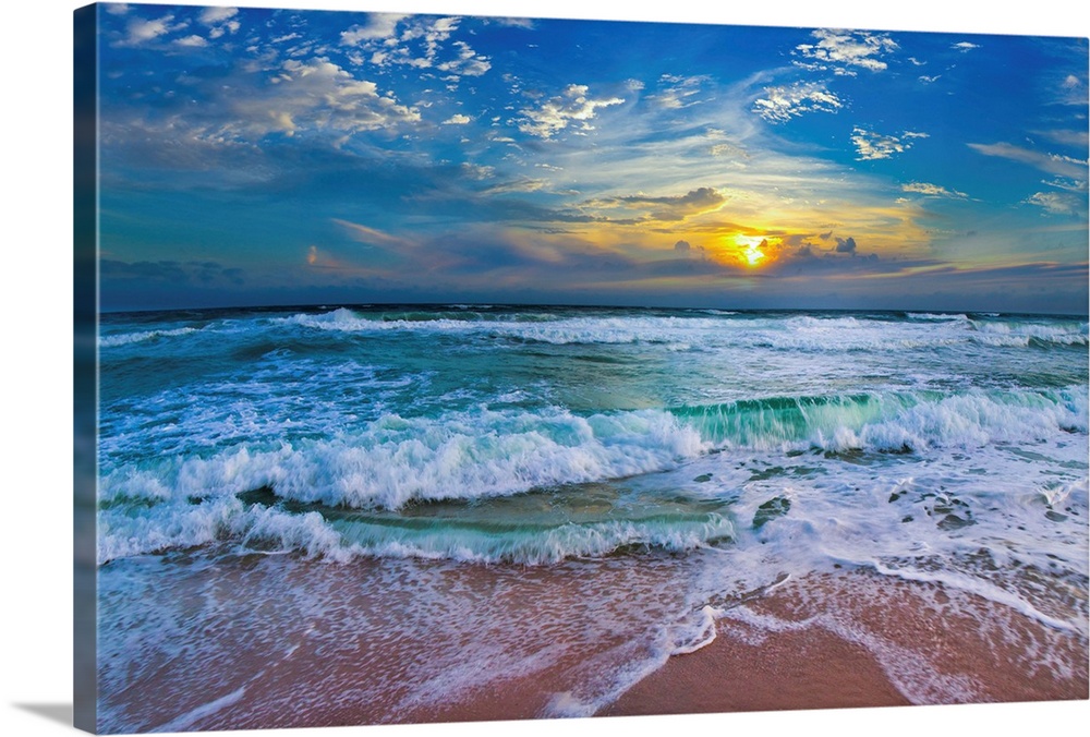 A glimpse of a yellow sunset within a cold blue sunset. Blue waves hit a tropical sea shore.
