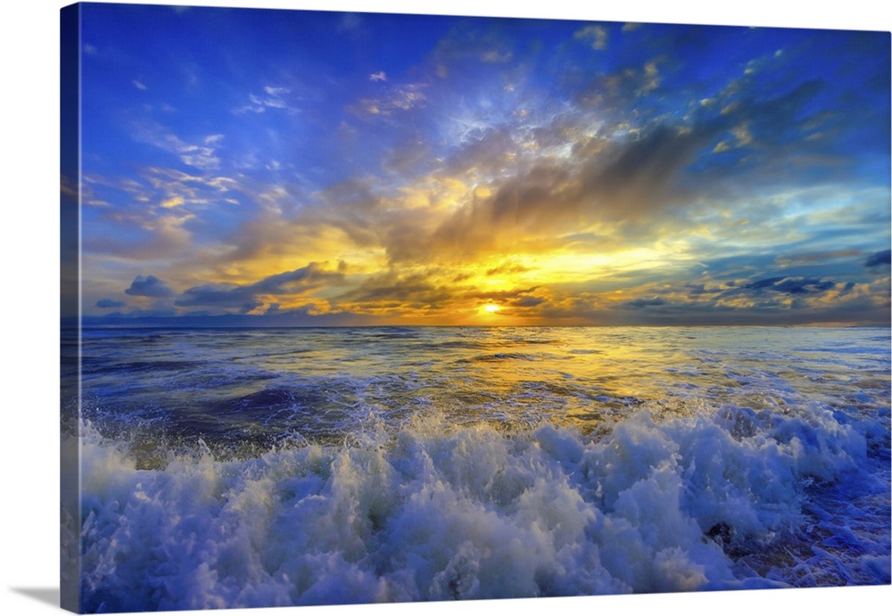 A brilliant gold and blue sunset over crashing ocean waves.