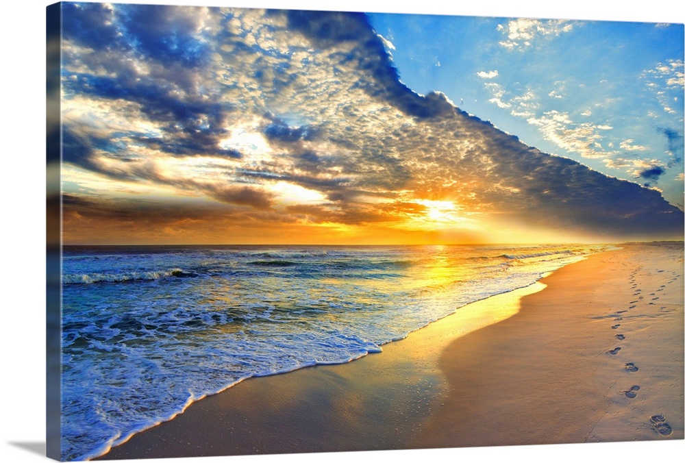 Bright golden sunset casts light onto the beach and blue seascape below. Landscape taken on Navarre Beach, Florida.