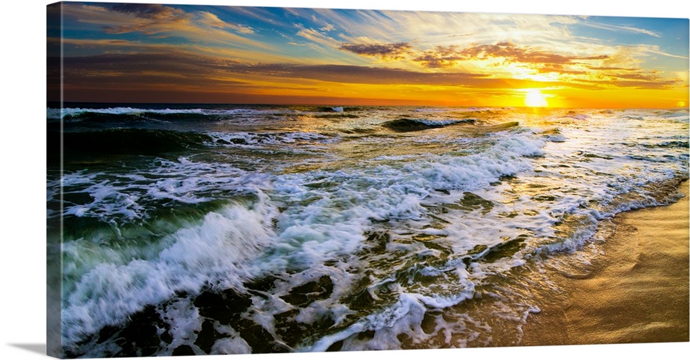 A panoramic landscape featuring a beautiful sunset over the sea. Golden light hits the crashing waves during the early mor...