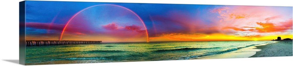A full rainbow across an ocean pier at sunset. The blue, purple, and red sky along with the green sea produce all the colo...