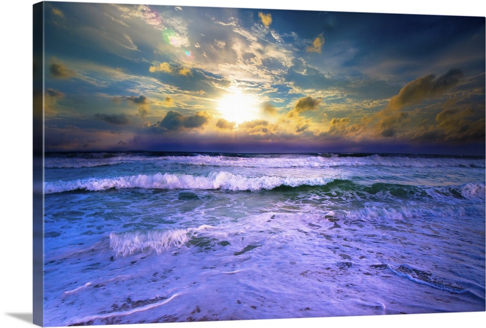 A bright yellow sunset with blue waves crashing on the beach.