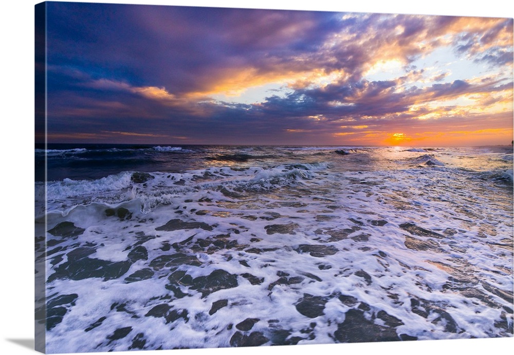 Breaking white waves in this seascape under an orange sunset.