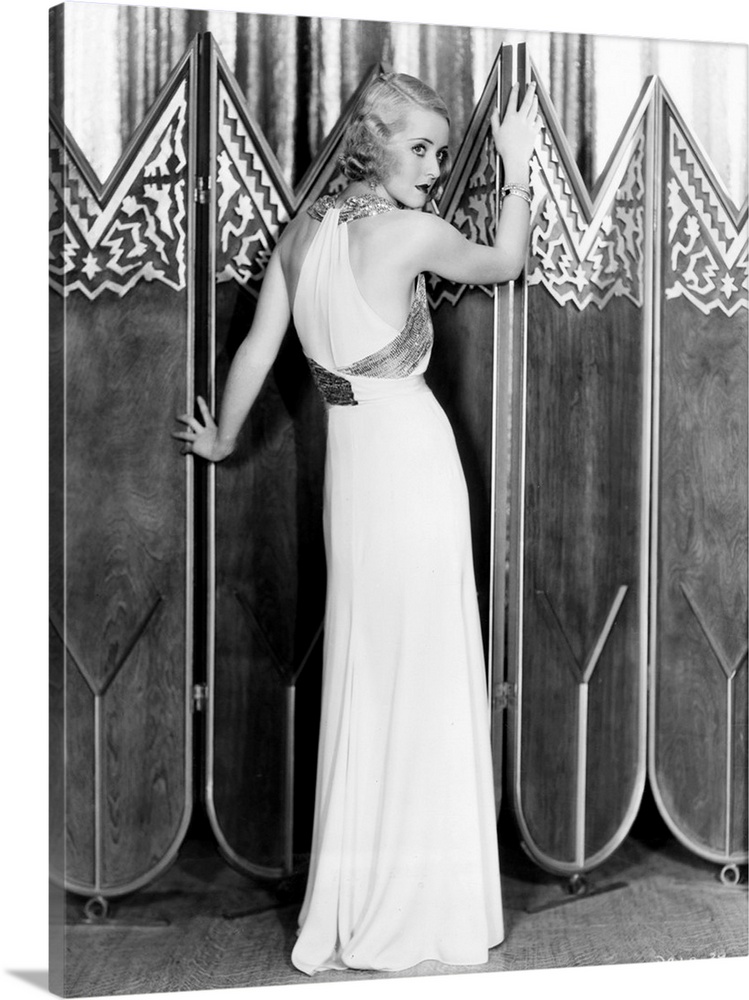 Bette Davis, modeling a white crepe evening gown with a silver sequined bodice sash, 1932.
