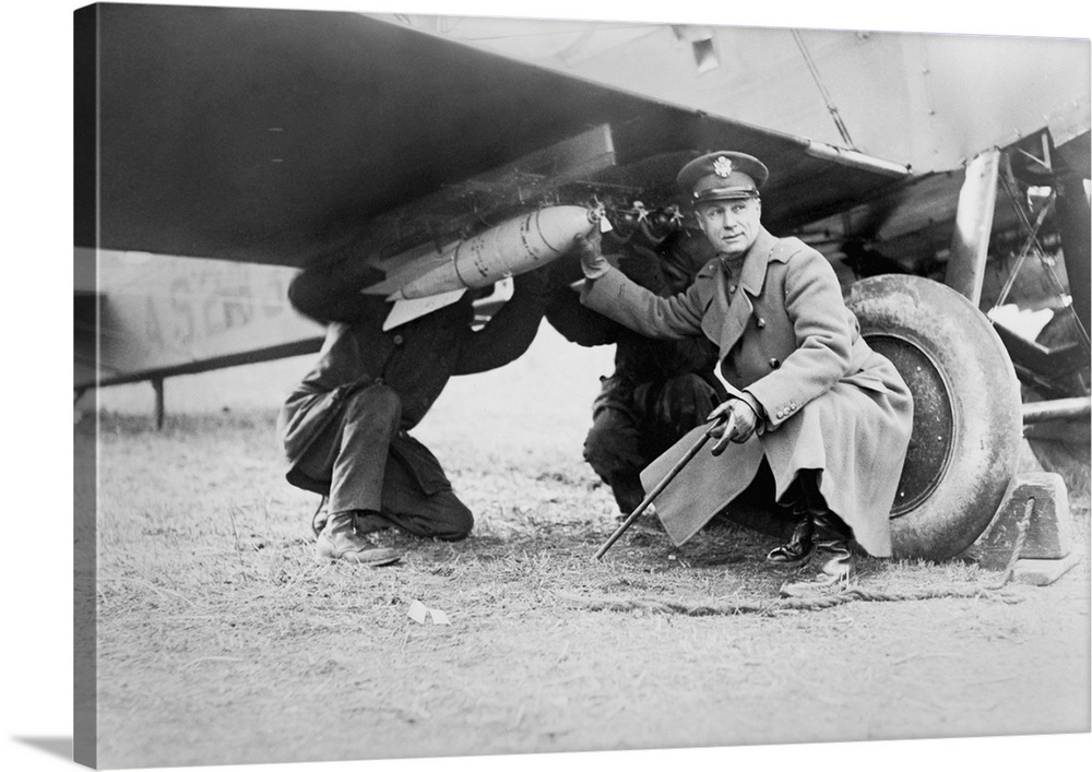 Brigadier General Billy Mitchell and another man, attaching a bomb under wing of airplane. Ca. 1925. He advocated military...