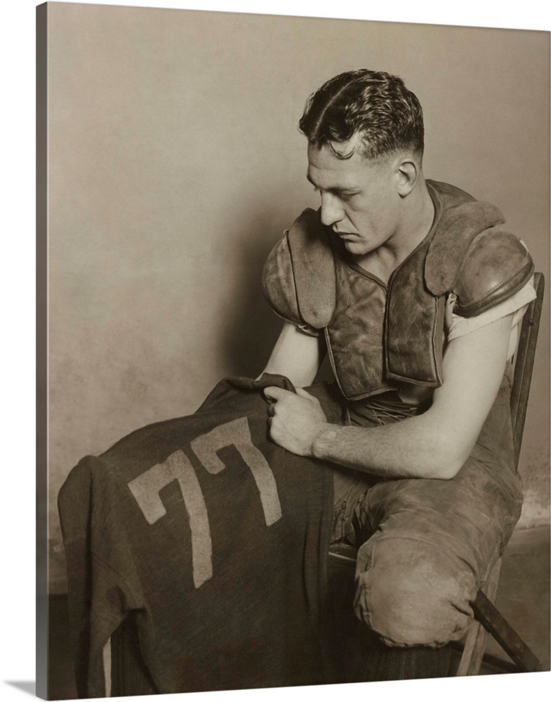 Harold 'Red' Grange holding his football jersey number. His number 77 was retired at the University of Illinois in 1925.