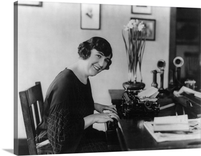 Smiling woman office worker seated at typewriter, in 1923