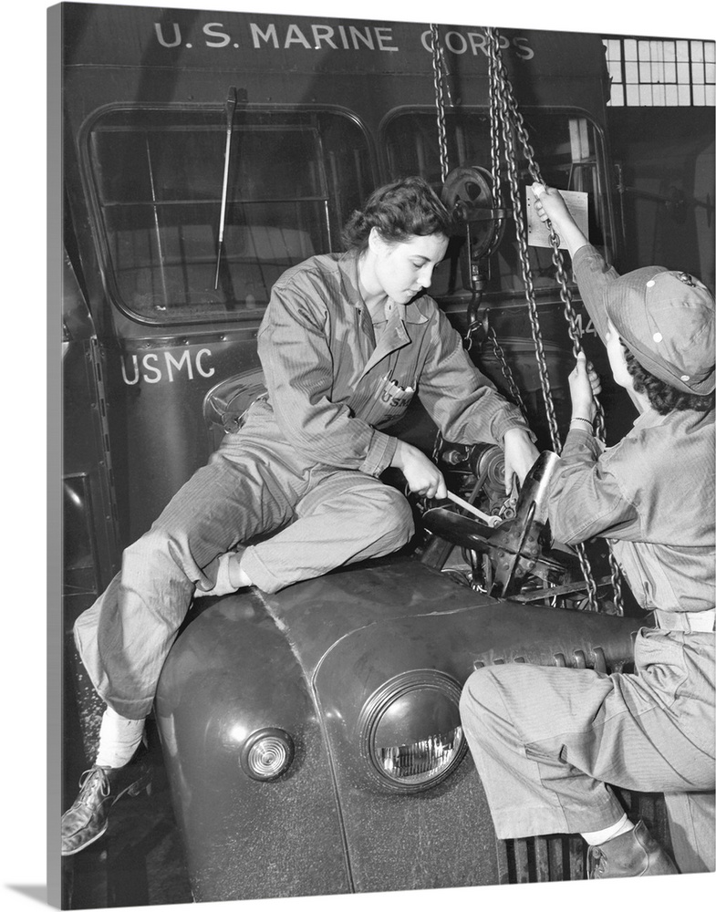 Women Marines lower a reconditioned engine back in place in a Marine Corps bus in 1943. They are graduates of Motor Transp...