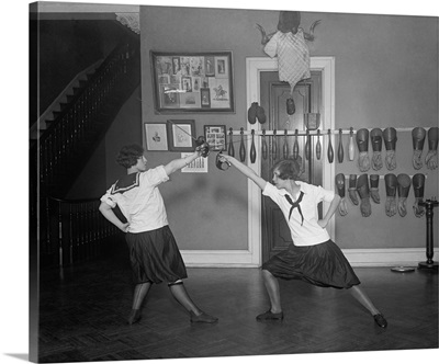 Young women in bloomers and middy shirts fencing
