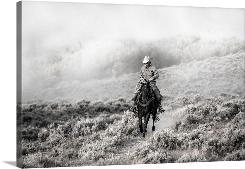Lone wrangler riding back from herding horses.