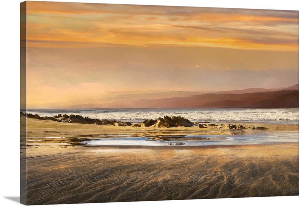 Landscape photograph of a warm toned sunset over a beach at low tide.