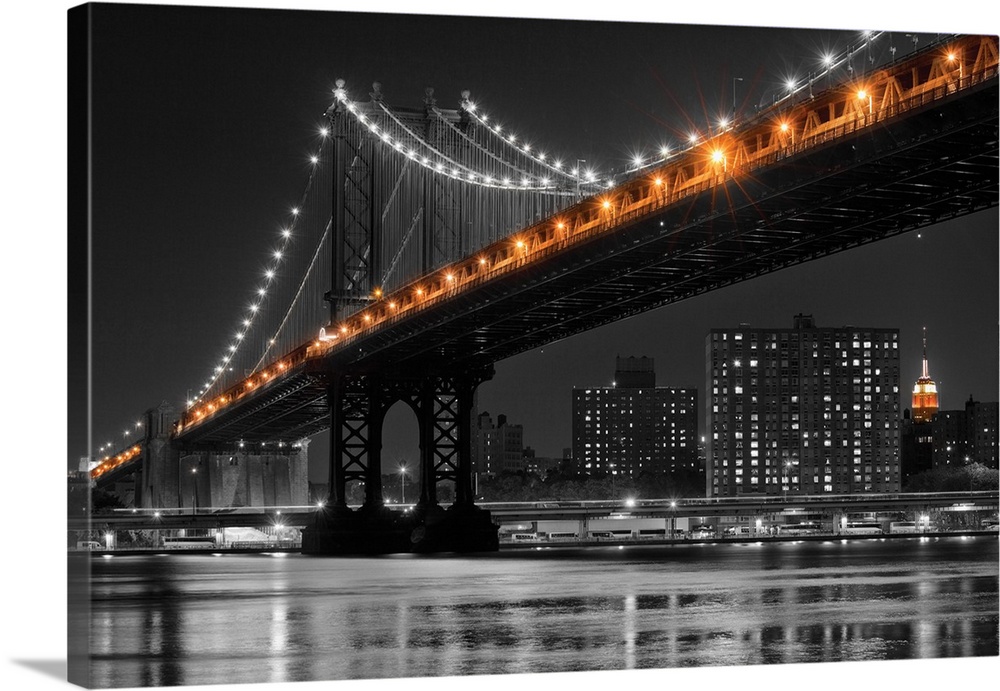 Black and white photograph of the Manhattan Bridge at night with only the lights in color.