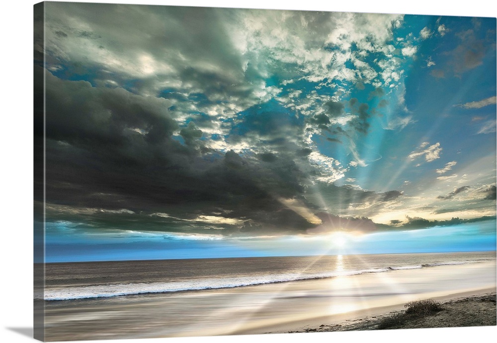 Stunning landscape photograph of the sun beaming over an empty beach with contrasting clouds in the sky.