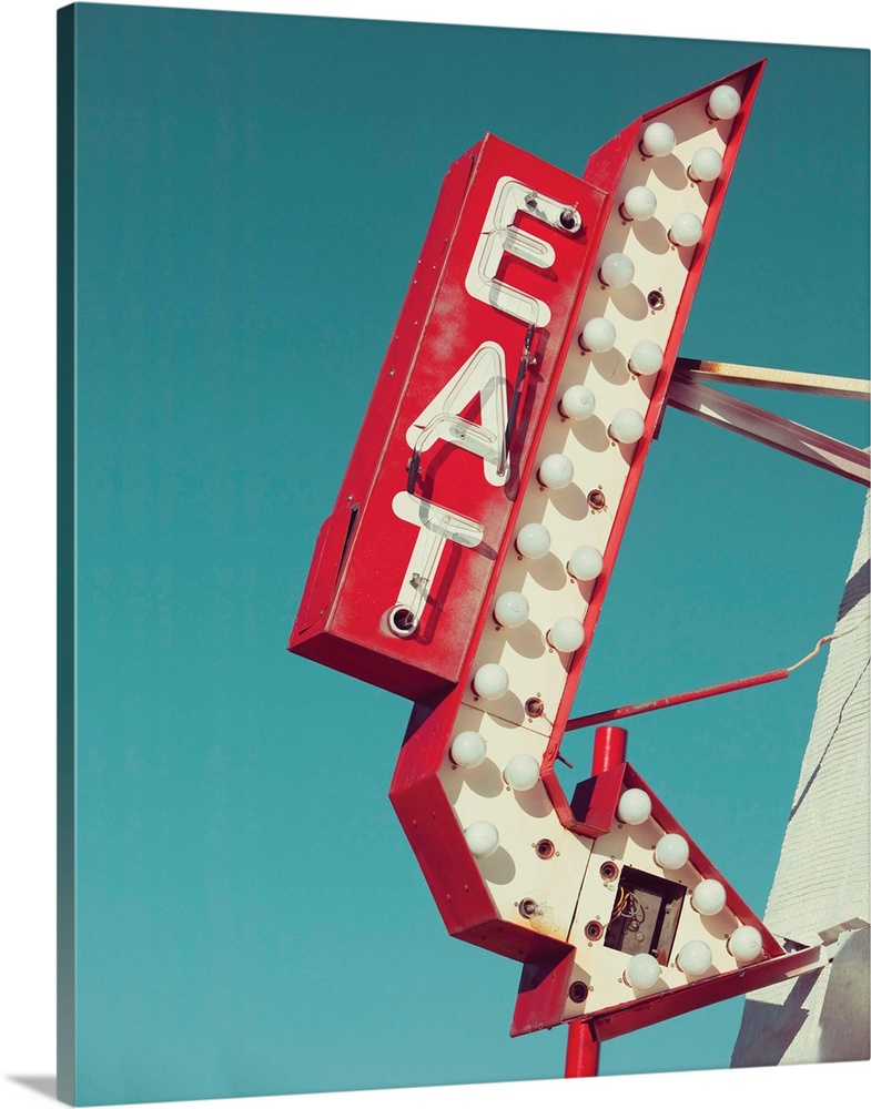 Photograph of a vintage red and white light up 'EAT' sign with an arrow on a blue sky background.