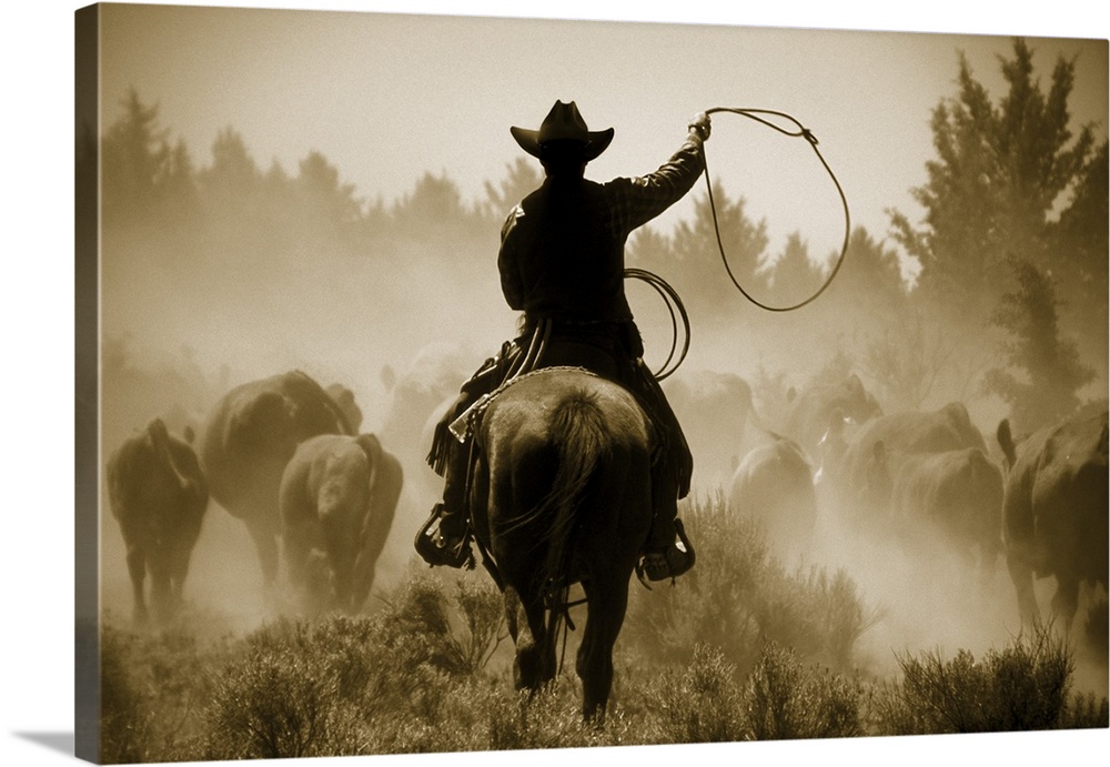 A photo of a cowboy rounding up cattle in a dusty field.