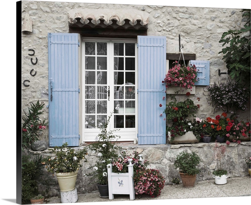 Photograph of a window with blue shutters on a house with potted plants surrounding it.