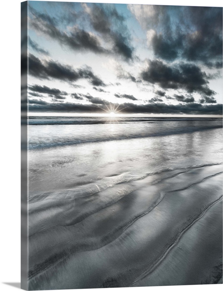 Black, blue, and white manipulated photograph of a seascape with the sun right on the horizon line.