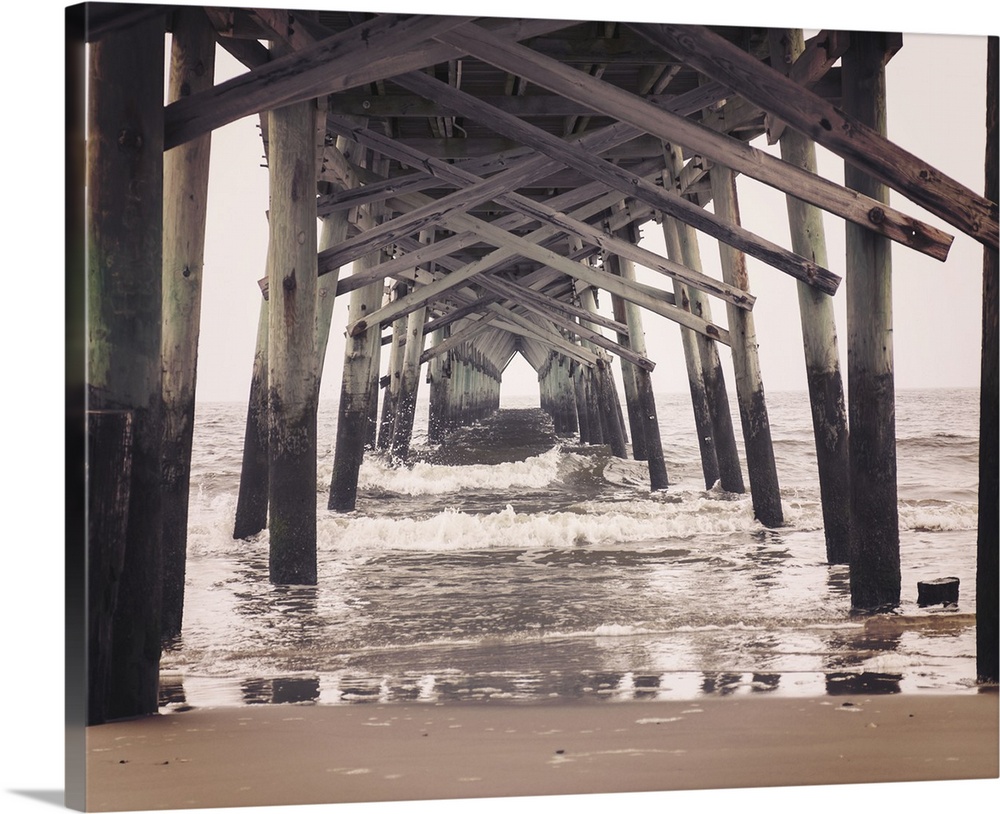 Photograph, with a faded look, of under a pier at the beach.