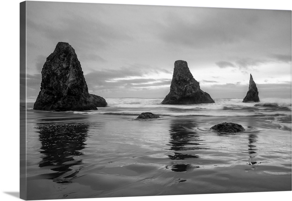 Black and white photograph of the Pacific Ocean with three rock formations near the shore in Bandon, Oregon.