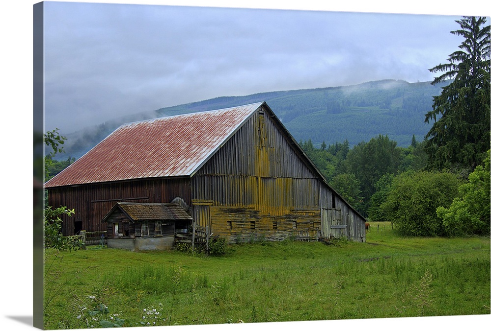 An old wooden barn in a rural field surrounded by fog.