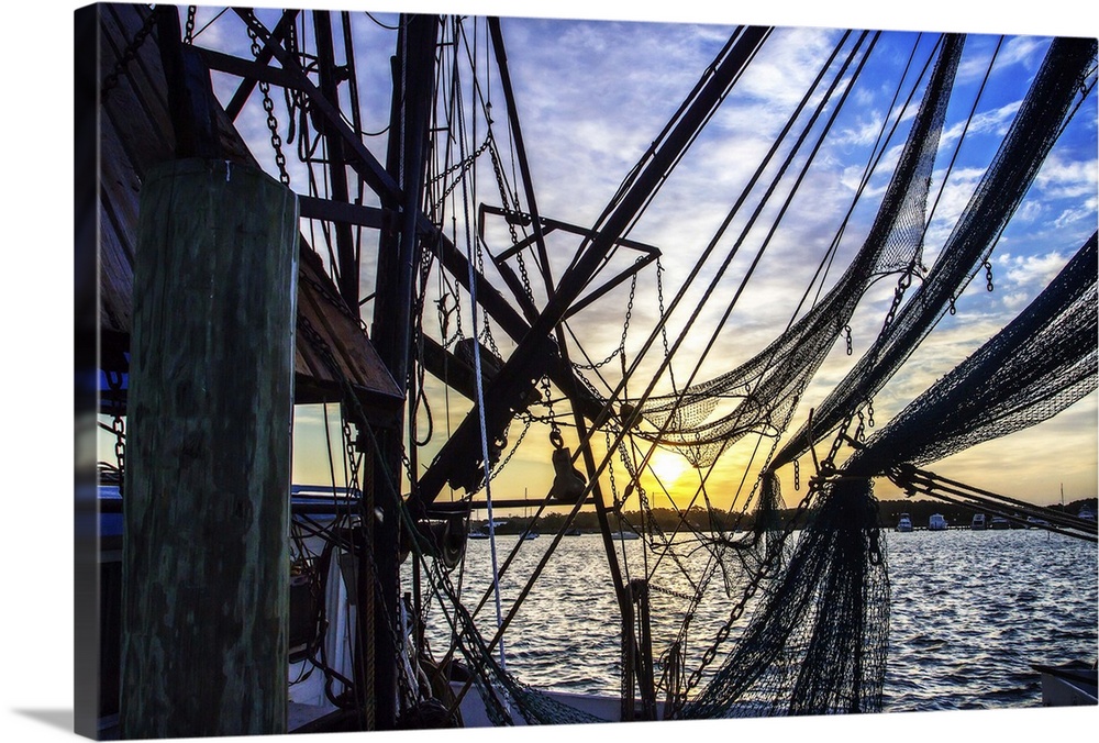 Photograph of the sunrise though boat lines and nets.