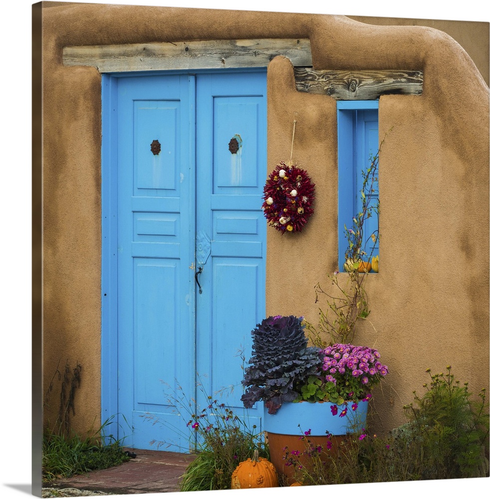 Photograph of a bright blue door and wreath in an adobe wall.