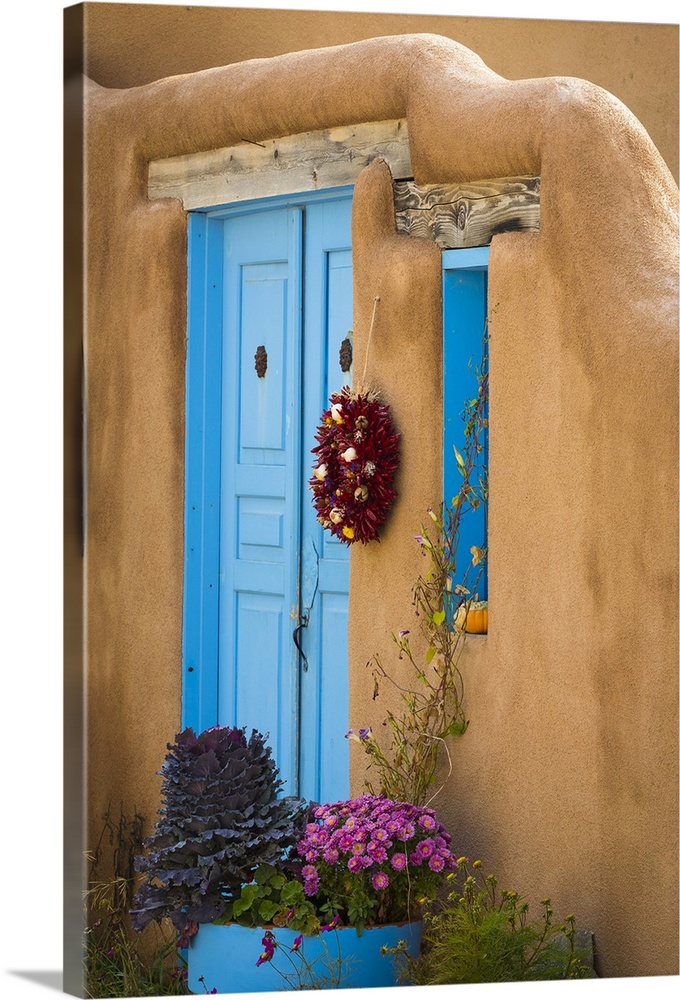 Photograph of a bright blue door and wreath in an adobe wall.