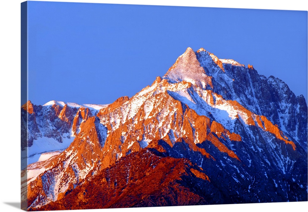 Photograph of Mount Williamson with golden lit snowy peaks at sunrise.