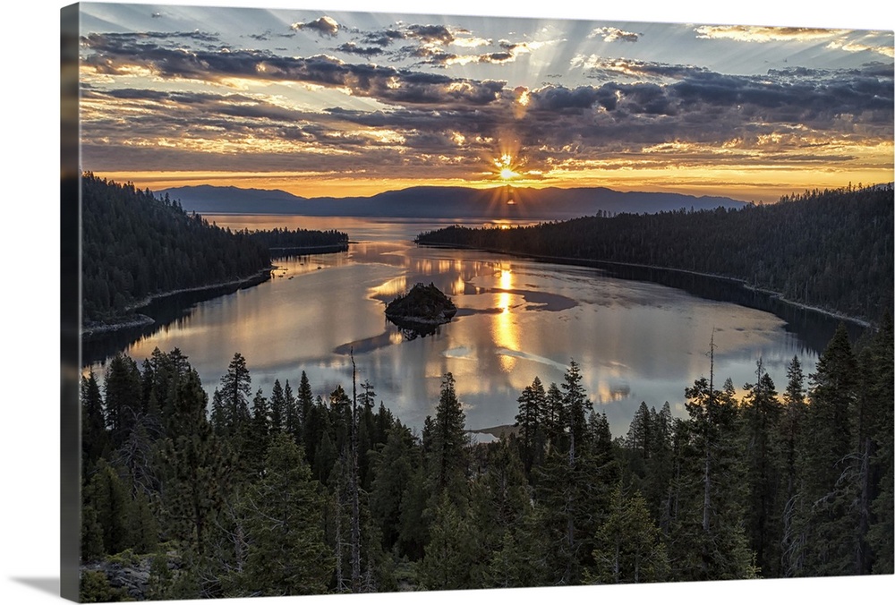 Landscape photograph of a beautiful sunset beaming through the clouds over Emerald Bay in California.