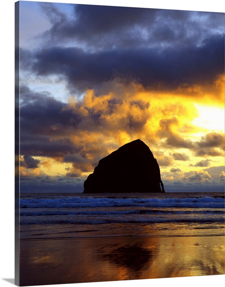 Silhouette photograph of a rock formation in the middle of the ocean with a colorful sunset in Oregon.
